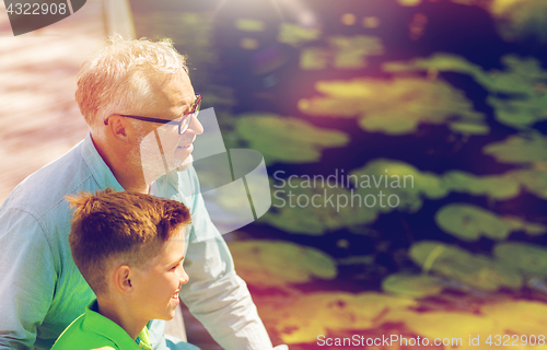 Image of grandfather and grandson sitting on river berth