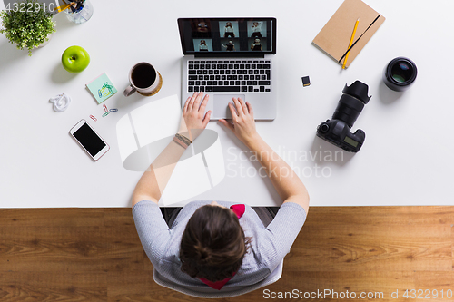 Image of woman with camera working on laptop at table