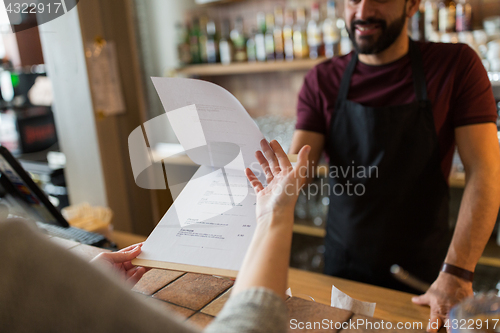 Image of bartender and customer menu at bar