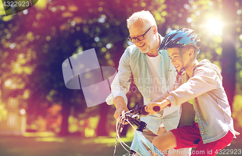 Image of grandfather and boy with bicycle at summer park