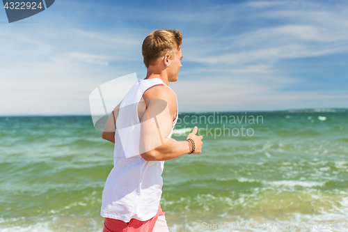 Image of happy man running along summer beach
