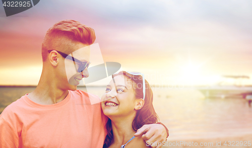 Image of happy teenage couple hugging on summer beach