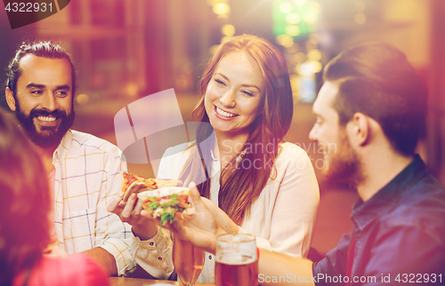 Image of friends eating pizza with beer at restaurant