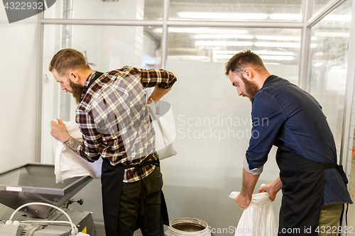 Image of men with malt bags and mill at craft beer brewery