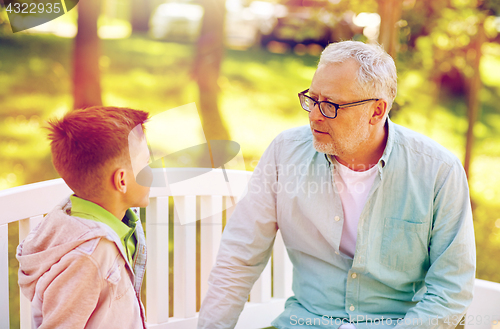 Image of grandfather and grandson talking at summer park