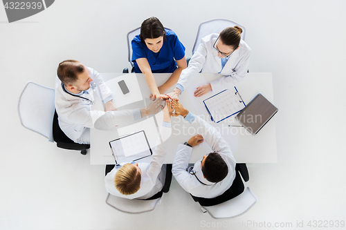 Image of group of doctors making high five at table