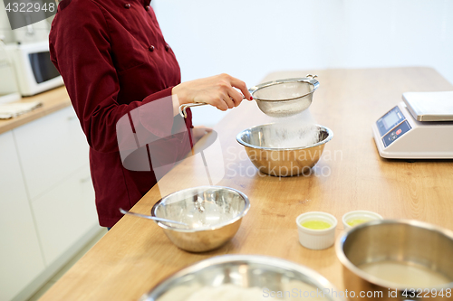 Image of chef sifting flour in bowl making batter or dough