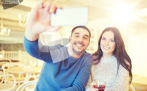 Image of couple taking smartphone selfie at cafe restaurant