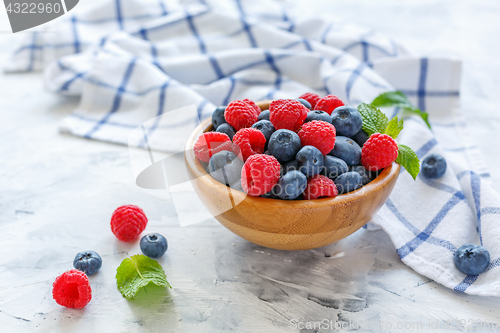 Image of Fresh raspberries and blueberries in wooden bowl.
