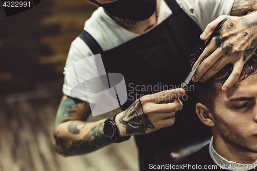 Image of Crop barber doing haircut for client