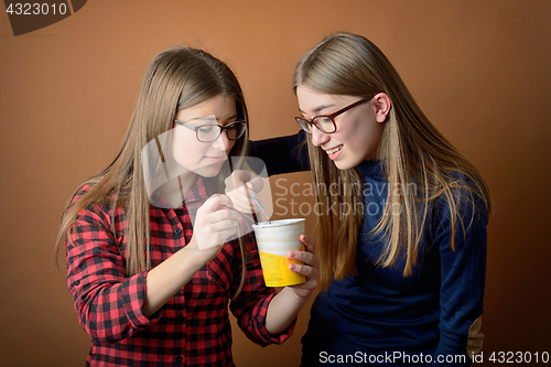 Image of Girls best friends sharing an ice-cream box