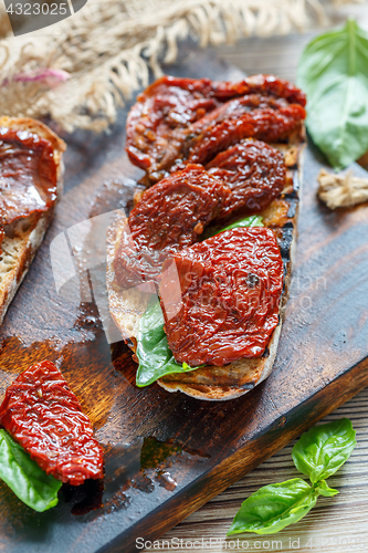 Image of Bruschetta with sun-dried tomatoes and basil leaves.