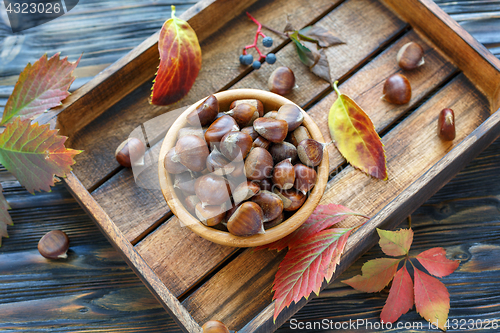 Image of Bowl with ripe chestnuts on a wooden box.