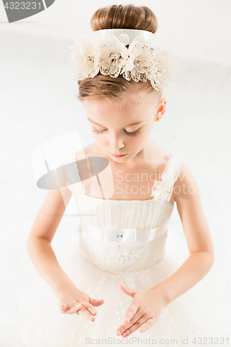 Image of Little ballerina girl in a tutu. Adorable child dancing classical ballet in a white studio.