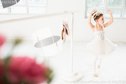 Image of Little ballerina girl in a tutu. Adorable child dancing classical ballet in a white studio.