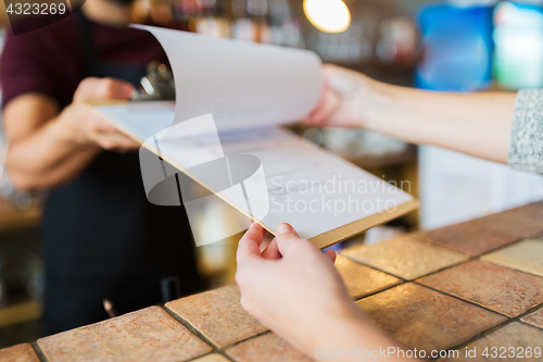 Image of bartender showing menu to customer at bar