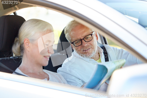 Image of happy senior couple with map driving in car