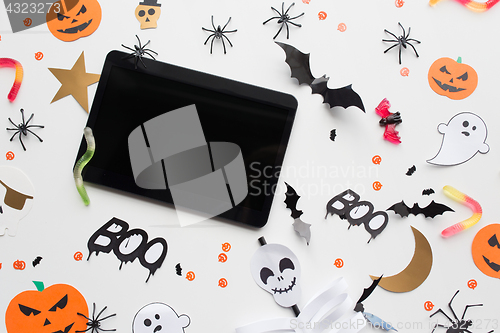 Image of tablet pc, halloween party decorations and candies