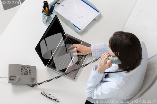Image of doctor with laptop calling on phone at clinic