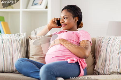 Image of happy pregnant woman calling on smartphone at home