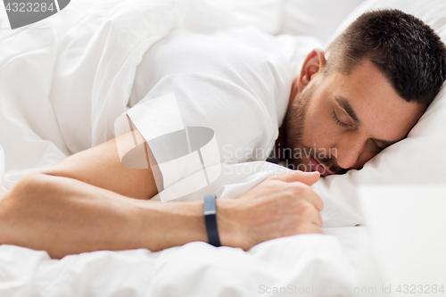 Image of man with smartwatch sleeping in bed