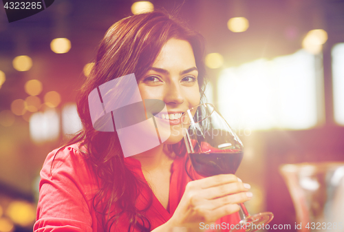 Image of smiling woman drinking red wine at restaurant