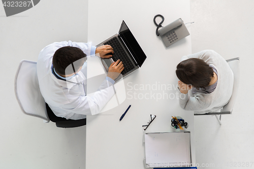 Image of doctor with laptop and woman patient at hospital