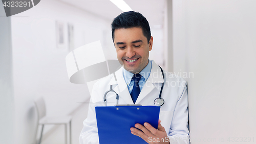 Image of happy doctor writing to clipboard at hospital