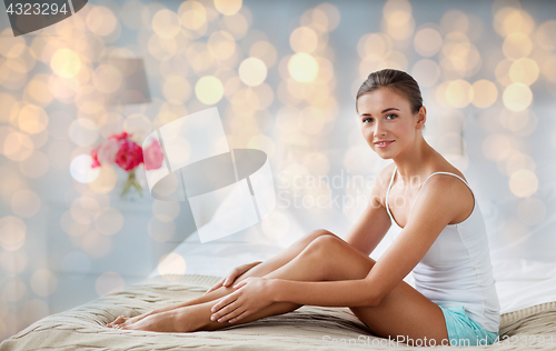 Image of beautiful woman with bare legs on bed at home