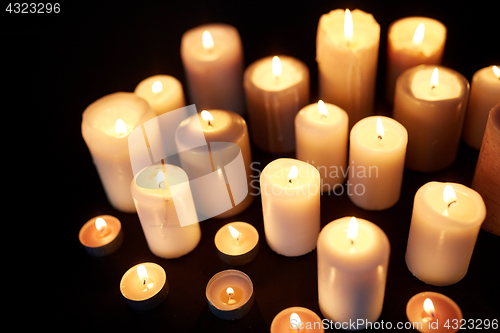 Image of candles burning in darkness over black background