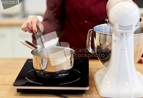 Image of chef measuring temperature in pot at kitchen