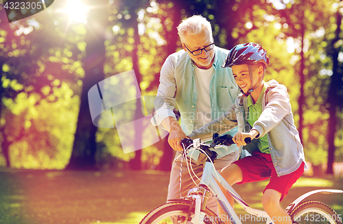 Image of grandfather and boy with bicycle at summer park