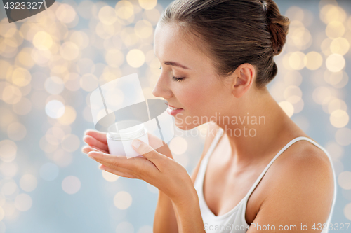 Image of close up of happy woman holding and smelling cream