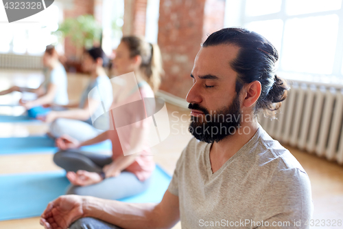 Image of man with group of people meditating at yoga studio