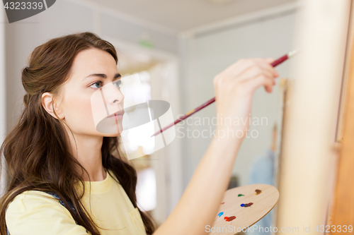 Image of student girl with easel painting at art school