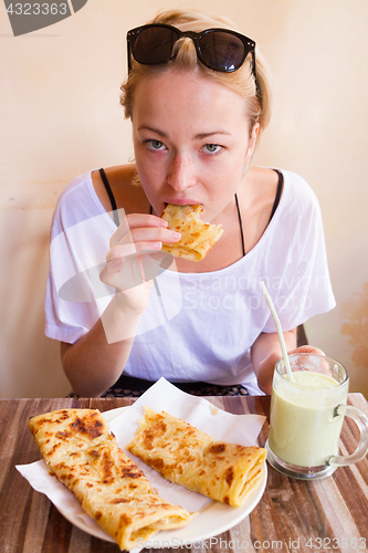 Image of Woman eating traditional moroccan breakfast in coffee shop.