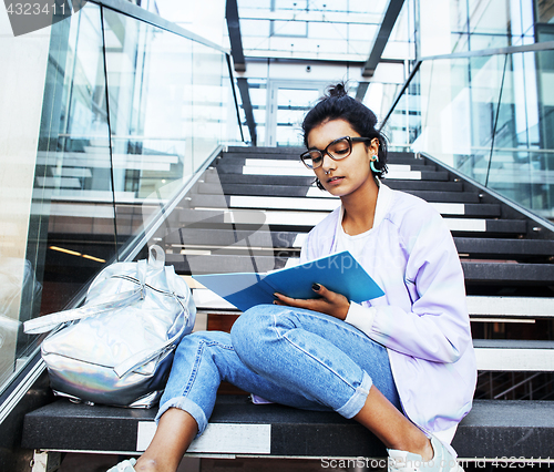 Image of young cute indian girl at university building sitting on stairs 