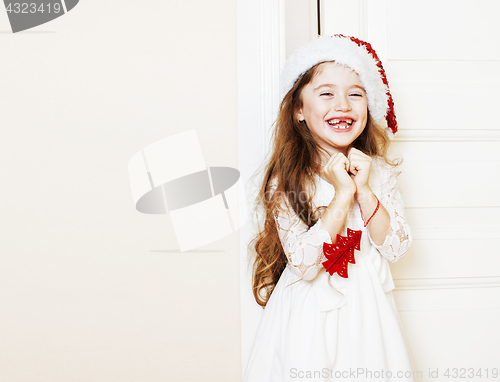 Image of little cute girl in santas red hat waiting for Christmas gifts. 