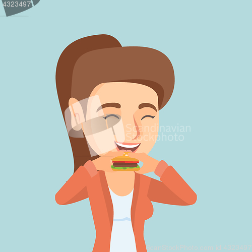 Image of Young caucasian joyful woman eating hamburger.