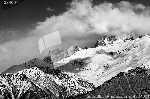 Image of Black and white view on snow mountains in clouds in winter sun d