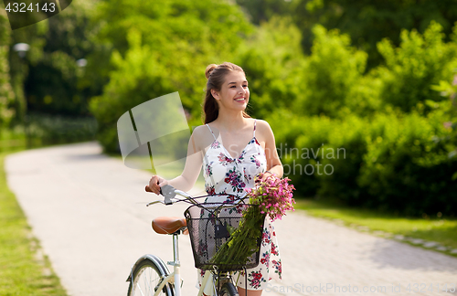 Image of happy woman riding fixie bicycle in summer park