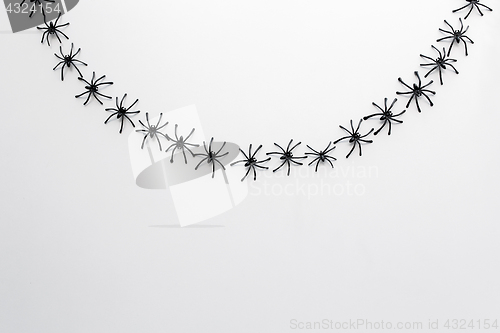 Image of black toy spiders chain over white background