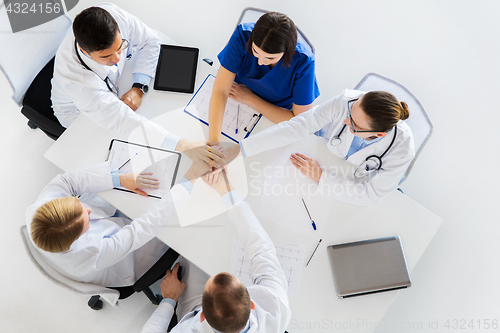 Image of group of doctors holding hands together at table