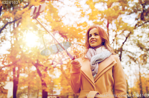 Image of woman taking selfie by smartphone in autumn park