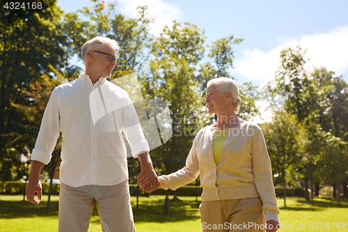 Image of happy senior couple walking at summer city park