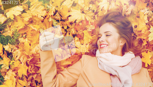 Image of woman on autumn leaves taking selfie by smartphone
