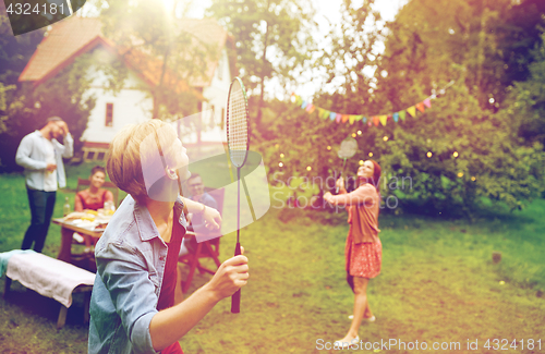 Image of happy friends playing badminton at summer garden