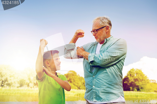 Image of happy grandfather and grandson showing muscles
