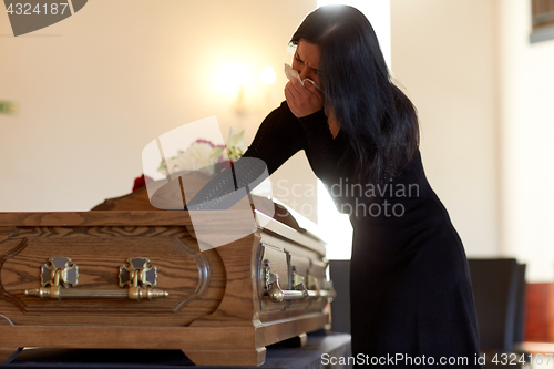 Image of woman with coffin crying at funeral in church