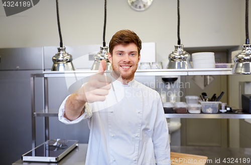 Image of happy chef at restaurant kitchen showing thumbs up